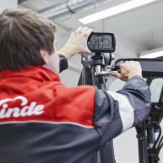 Mechanik společnosti Linde Material Handling připevňuje zařízení Linde BlueSpot na střechu vozíku.