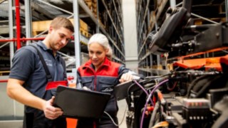 Dva servisní technici společnosti Linde Material Handling se dívají na notebook vedle vozíku.