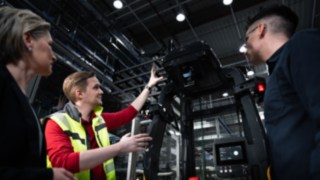 Tři osoby stojí před automatizovaným vozíkem společnosti Linde Material Handling.