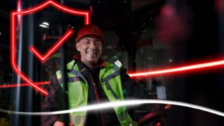 Osoba v pracovním oděvu a ochranné přilbě sedí ve vysokozdvižném vozíku Linde Osoba v pracovním oděvu a ochranné přilbě sedí ve vysokozdvižném vozíku Linde