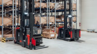 Dva vysokozdvižné vozíky pro velmi úzké uličky od společnosti Linde Material Handling s integrovaným osobním ochranným zařízením před skladem s úzkými uličkami