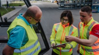 Tři osoby v reflexních vestách při rozhovoru: Bezpečnostní poradenství u zákazníka na místě. Tři osoby v reflexních vestách při rozhovoru: Bezpečnostní poradenství u zákazníka na místě.