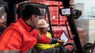 Bezpečnostní technik společnosti Linde Material Handling ukazuje řidiči vysokozdvižného vozíku údaje na tabletu. Bezpečnostní technik společnosti Linde Material Handling ukazuje řidiči vysokozdvižného vozíku údaje na tabletu.