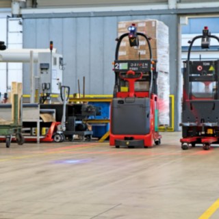 Dva automatické vysokozdvižné vozíky L-MATIC přepravují zboží mezi balicí linkou a průběžným skladem.