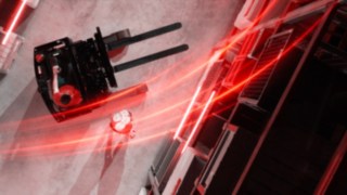 Pohled z ptačí perspektivy na retrak Ri16 od společnosti Linde Material Handling s červenými světelnými stopami, vedle kterého je další člověk.